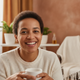 A happy woman in her mid-30s smiles warmly, representing a satisfied customer.